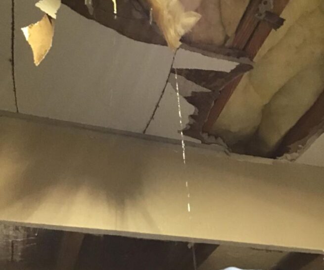 Water drains from ceiling where water tank is stationed on upper floor